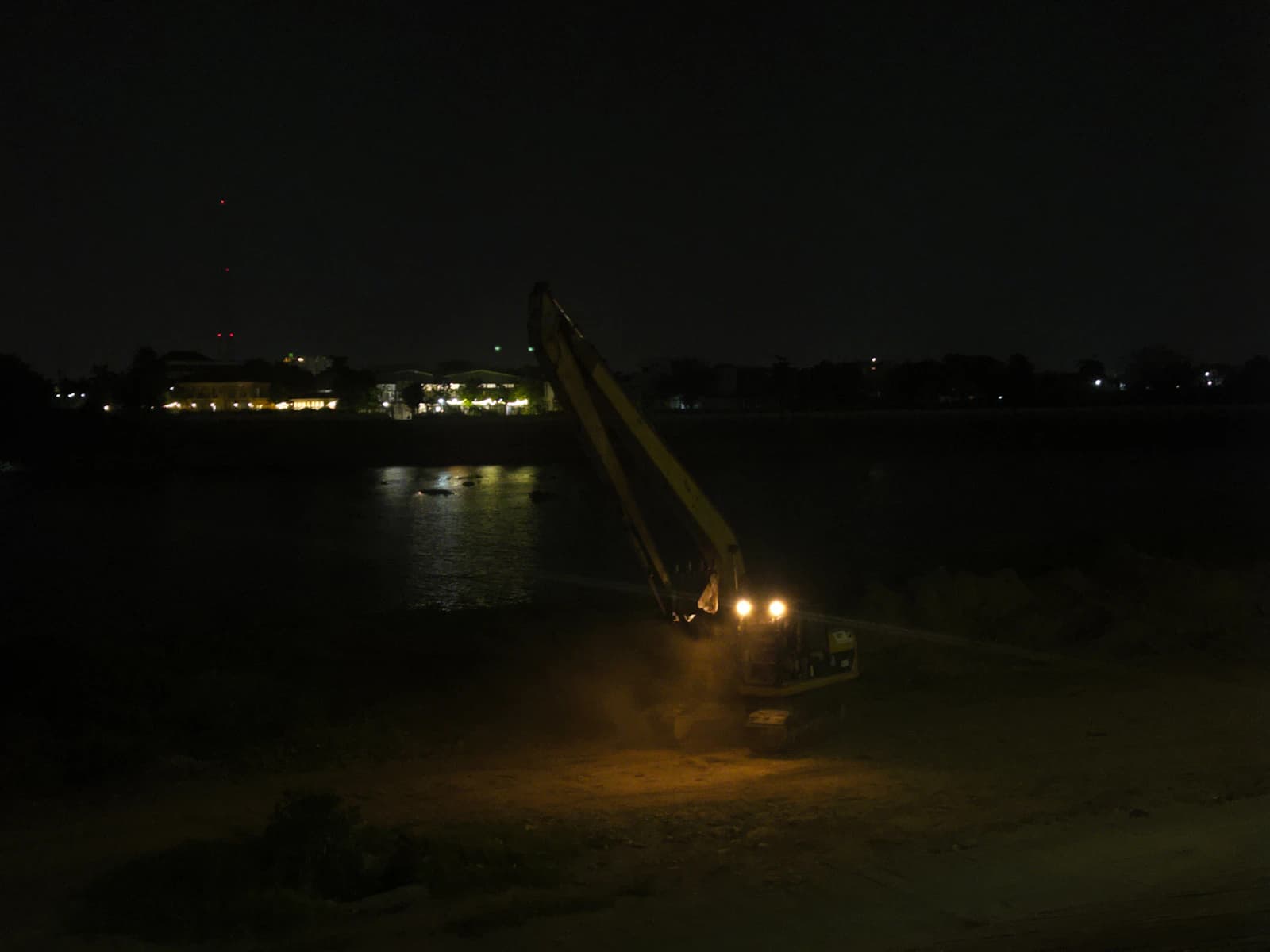Excavator working at night under machine lights during an emergency repair call-out